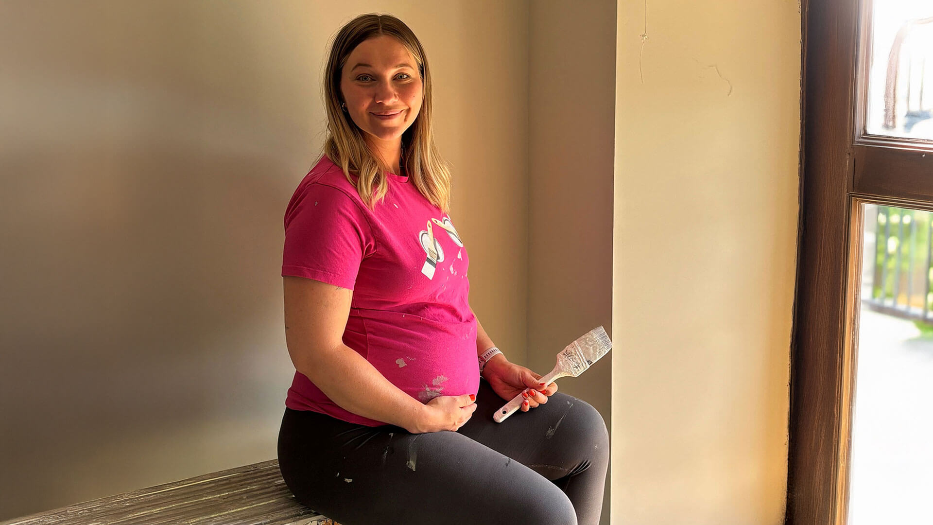 Pregnant woman holding decorating paint brush 